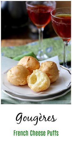 gougeres on a plate next to two glasses of wine