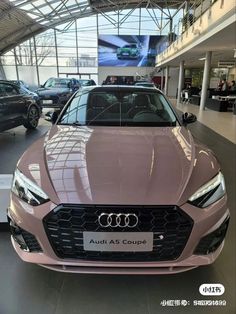 an audi car is parked in a showroom with other cars on display behind it