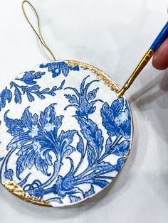 a blue and white plate being painted with gold