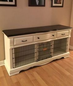 a white dog crate with two dogs in it and pictures on the wall behind it