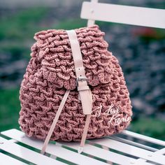 a pink crocheted backpack sitting on top of a white bench