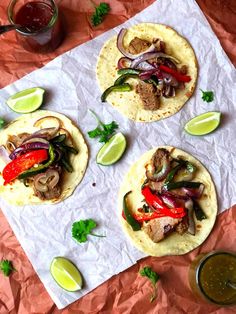 three tortillas with meat, peppers and onions on a piece of parchment paper