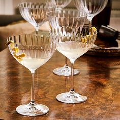 four wine glasses sitting on top of a wooden table