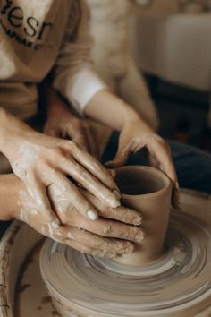 a person is making a vase out of clay on a potter's wheel with their hands