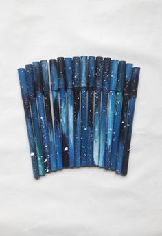 blue and black marbled pens lined up in a row on a white sheeted surface