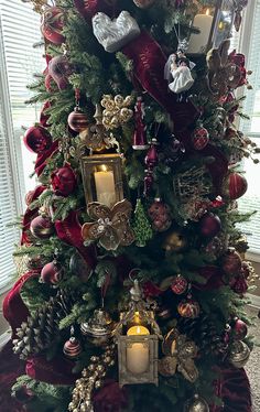 a christmas tree decorated with red and gold ornaments, candles and other holiday decor items