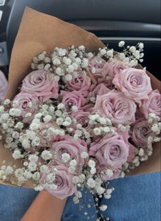 a bouquet of pink roses and baby's breath is held in someone's lap