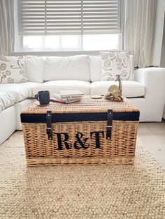 a wicker trunk sitting on top of a rug in front of a white couch