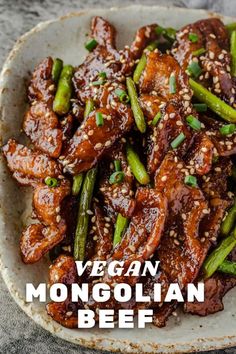 a white plate topped with meat and asparagus covered in sesame seeds next to a fork