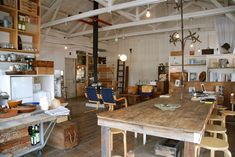 a large wooden table sitting in the middle of a room with lots of shelves and chairs