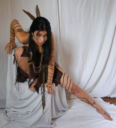 a woman with tattoos on her body posing for the camera in front of a white backdrop