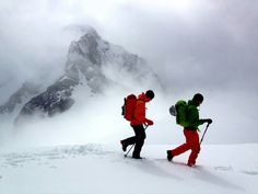 three skiers trekking through the snow in front of a mountain