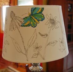 a lamp that is on top of a table with a butterfly painted on the lampshade