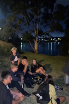 a group of young people sitting on the ground next to each other at night time