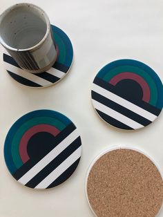 three coasters with different designs on them sitting next to a cup and saucer