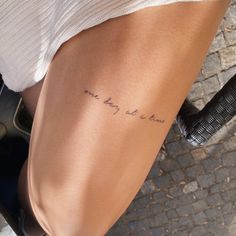 a woman with a tattoo on her leg that reads, one day at a time