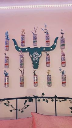 there are many bottles hanging on the wall with an animal head above them and flowers growing out of each bottle