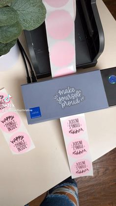 some pink and white stickers sitting on top of a desk next to a printer