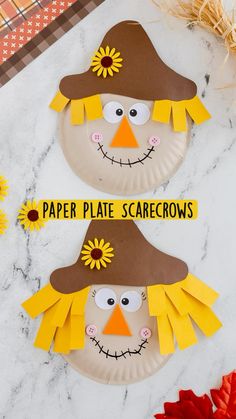 two paper plate scarecrows sitting on top of a table