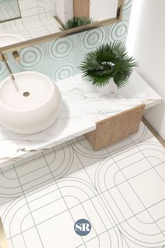 a white sink sitting on top of a bathroom counter next to a mirror and potted plant