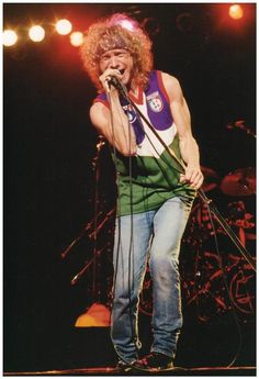 an image of a man that is on stage with a microphone in his hand and singing