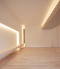 an empty room with white walls and wooden floors is lit by light from the ceiling