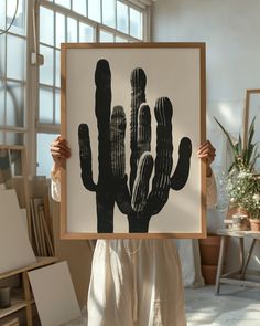 a woman holding up a black and white cactus print