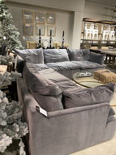 a living room filled with lots of furniture next to a christmas tree in a store