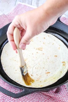 a person using a brush to stir up food in a skillet