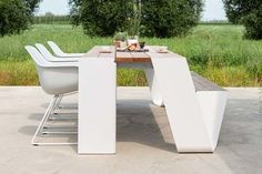 an outdoor dining table with white chairs and a vase filled with flowers sitting on top of it