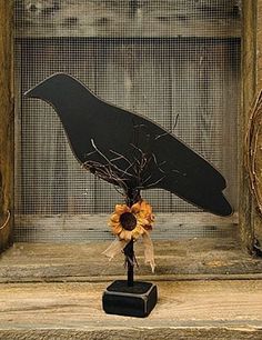 a black bird sculpture with sunflowers in it's beak on a stand