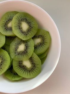 a white bowl filled with sliced kiwis on top of a table