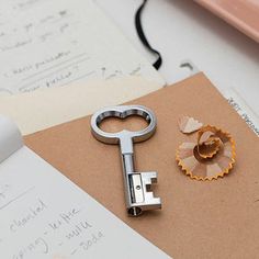 there is a metal key on top of a piece of paper next to a hole punch