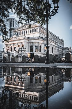 an old building is reflected in the water near a lamp post and street light pole