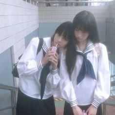 two girls in school uniforms standing next to each other