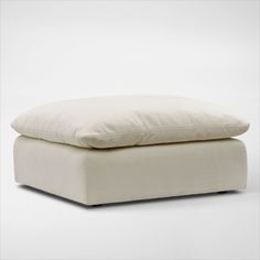 a white pillow sitting on top of an ottoman