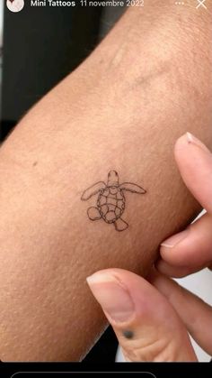 a small tattoo on the arm of a woman's left arm, with a turtle drawn