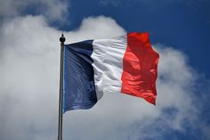 the french flag is flying high in the blue sky with white and red clouds behind it