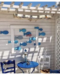 a blue table and chairs sitting under a pergolated trellis on the side of a building