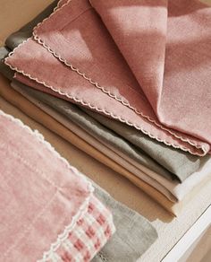 folded linens are sitting on top of each other in different colors and patterns, including pink