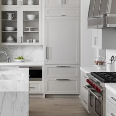 a kitchen with marble counter tops and white cabinets, along with stainless steel oven hoods