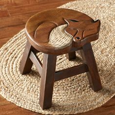 a wooden stool with an animal carving on the top and bottom, sitting on a rug