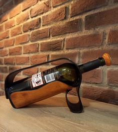 a wine bottle holder with a wooden handle on a table in front of a brick wall