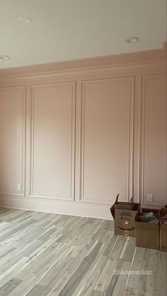 an empty room with hard wood flooring and pink paint on the walls, along with boxes