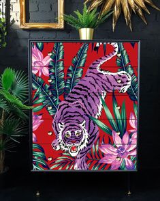 a tiger painted on a chest of drawers next to plants