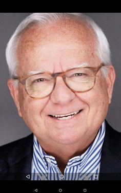 an older man with glasses smiling for the camera