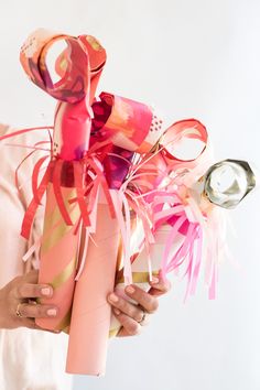 a woman holding a vase filled with pink flowers and ribbons on top of her head