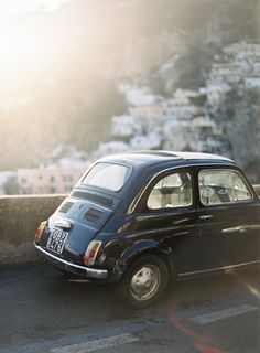 an old black car parked on the side of a road