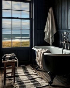 a bath tub sitting in front of a window next to a wooden table and chair