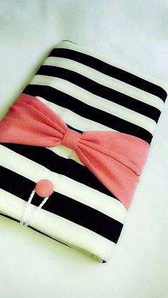 a black and white striped ipad case with a pink bow on the front, sitting on a table